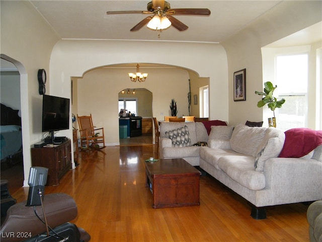 living room with ceiling fan with notable chandelier and hardwood / wood-style floors