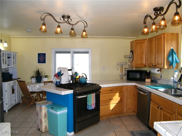 kitchen featuring tile counters, black appliances, light tile patterned floors, sink, and pendant lighting