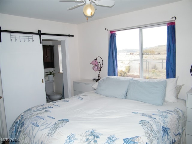 bedroom featuring a mountain view, a barn door, and ceiling fan