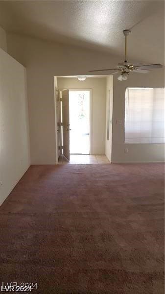 spare room featuring ceiling fan, lofted ceiling, carpet floors, and a textured ceiling