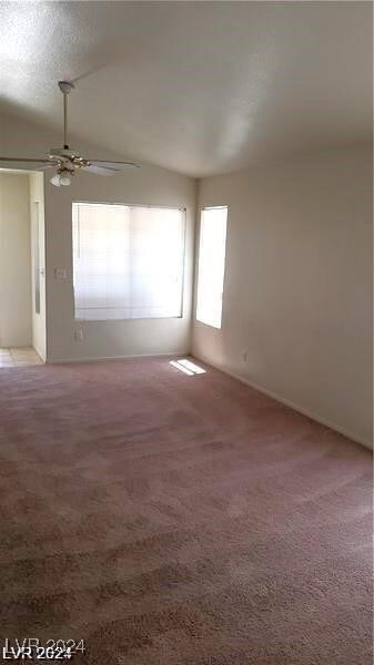 spare room featuring vaulted ceiling, carpet, and ceiling fan