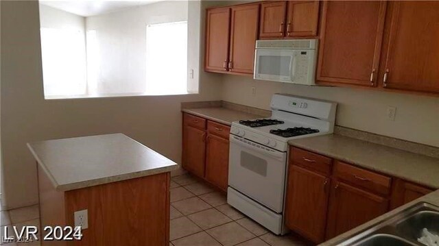 kitchen with a center island, light tile patterned floors, and white appliances