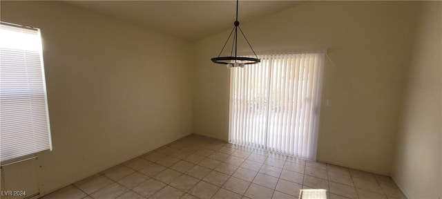 tiled empty room with lofted ceiling and a chandelier