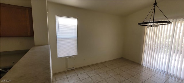 unfurnished dining area featuring an inviting chandelier and light tile patterned flooring