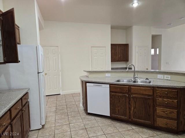 kitchen featuring sink, light stone counters, dark brown cabinets, light tile patterned floors, and white appliances