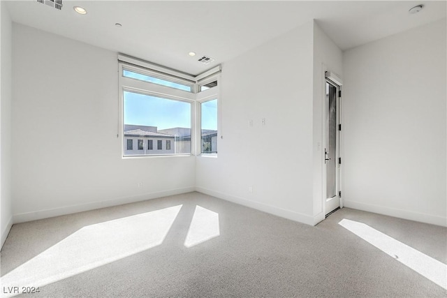 spare room with light carpet, recessed lighting, visible vents, and baseboards