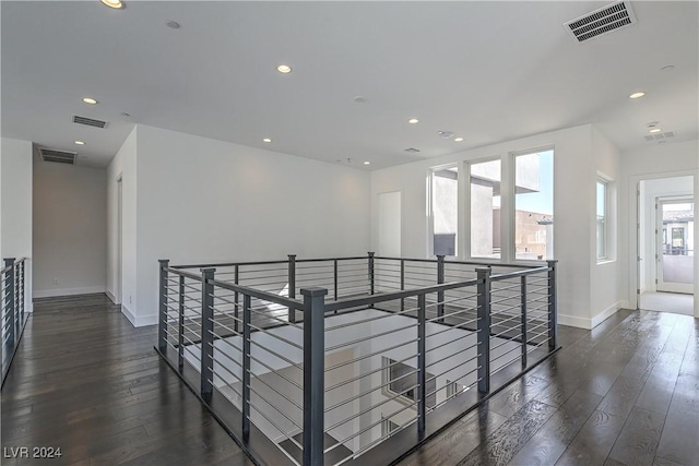 hallway featuring hardwood / wood-style flooring, visible vents, and an upstairs landing