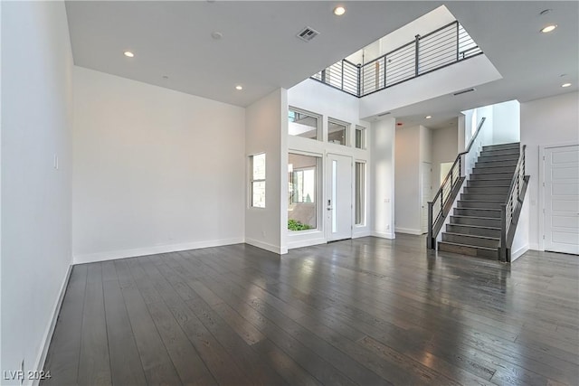 unfurnished living room with dark wood-type flooring, stairway, visible vents, and baseboards