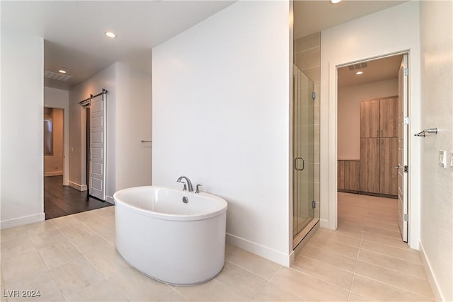 bathroom with tile patterned flooring, a freestanding tub, a shower stall, and recessed lighting