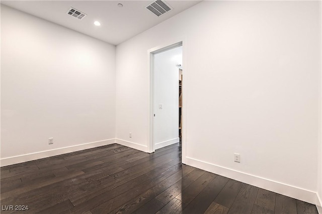 empty room featuring dark wood-style floors, baseboards, visible vents, and recessed lighting