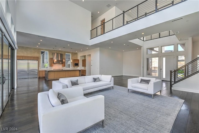 living area featuring a high ceiling, stairs, visible vents, and dark wood-type flooring