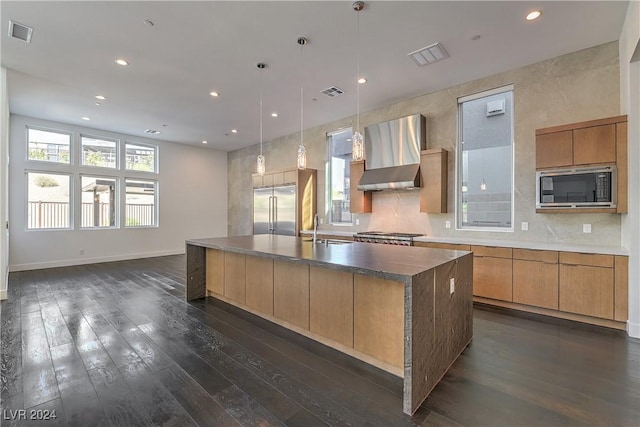 kitchen with dark wood-type flooring, visible vents, wall chimney exhaust hood, and built in appliances