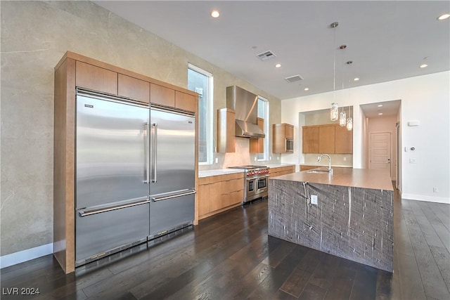 kitchen with dark wood-style floors, high end appliances, a sink, modern cabinets, and wall chimney exhaust hood