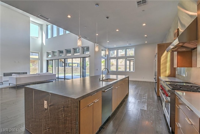 kitchen with premium appliances, a sink, visible vents, wall chimney exhaust hood, and modern cabinets