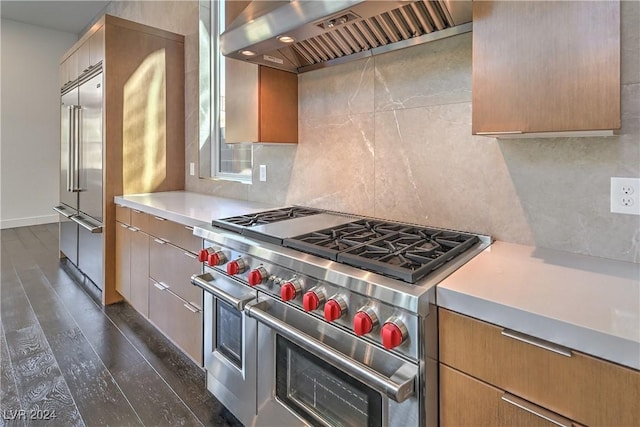 kitchen with dark wood-type flooring, light countertops, decorative backsplash, wall chimney exhaust hood, and high end appliances