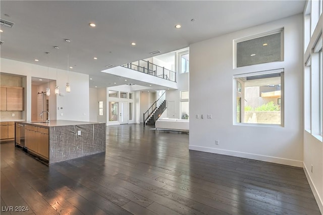 unfurnished living room featuring dark wood finished floors, a sink, baseboards, and recessed lighting