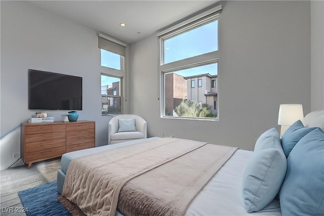 bedroom with light wood-style flooring, a high ceiling, and recessed lighting