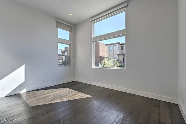 spare room with dark wood-style floors, a high ceiling, and baseboards