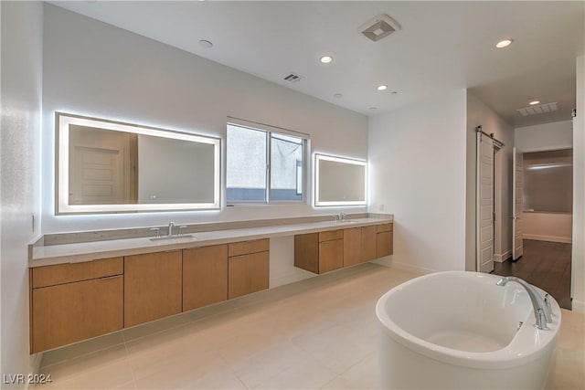 bathroom featuring double vanity, a freestanding tub, a sink, and visible vents