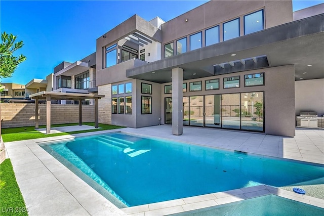 view of pool featuring exterior kitchen, a patio area, a grill, and fence