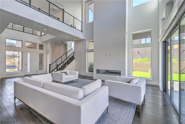 living area with dark wood-type flooring, stairway, and baseboards