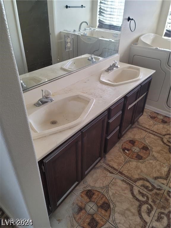 bathroom featuring vanity, a tub to relax in, tile patterned floors, and washer / clothes dryer