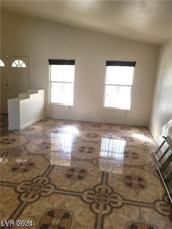 empty room featuring a wealth of natural light and vaulted ceiling