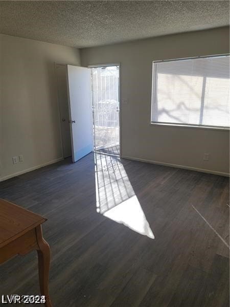 empty room with dark wood-type flooring and a textured ceiling