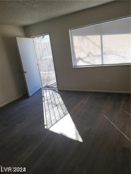 unfurnished room featuring dark hardwood / wood-style floors and a textured ceiling