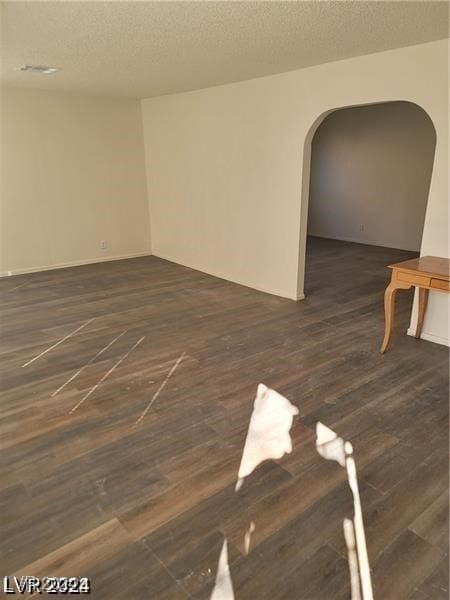 spare room with a textured ceiling and dark hardwood / wood-style flooring