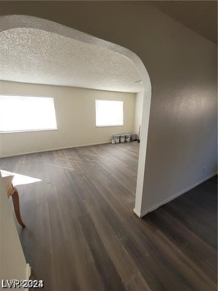 spare room with dark hardwood / wood-style floors and a textured ceiling