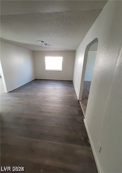 empty room featuring dark wood-type flooring and a textured ceiling