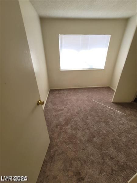 unfurnished room featuring dark colored carpet and a textured ceiling