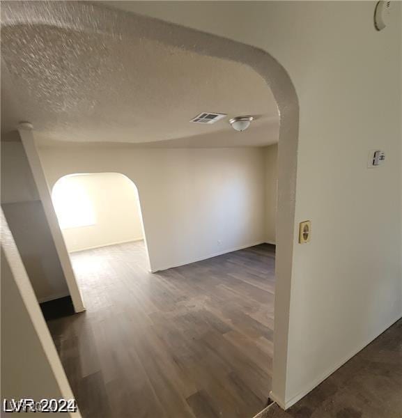 hallway with dark wood-type flooring and a textured ceiling