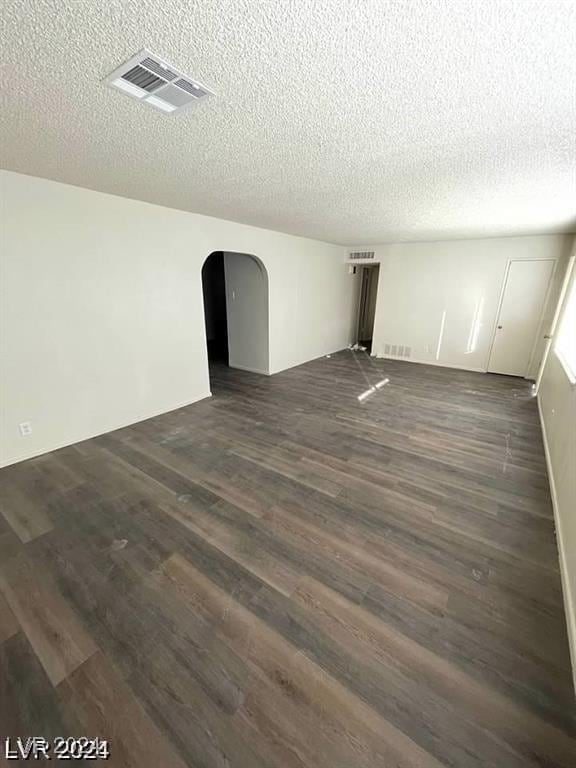 empty room featuring dark wood-type flooring and a textured ceiling