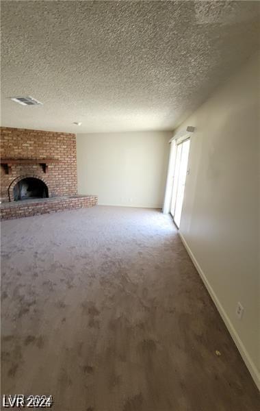 unfurnished living room featuring a fireplace, a textured ceiling, and carpet