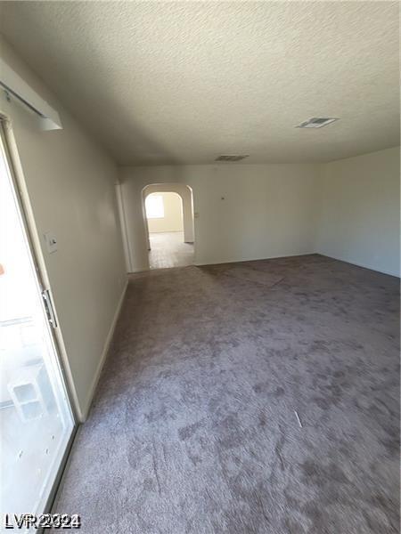 carpeted empty room with a textured ceiling