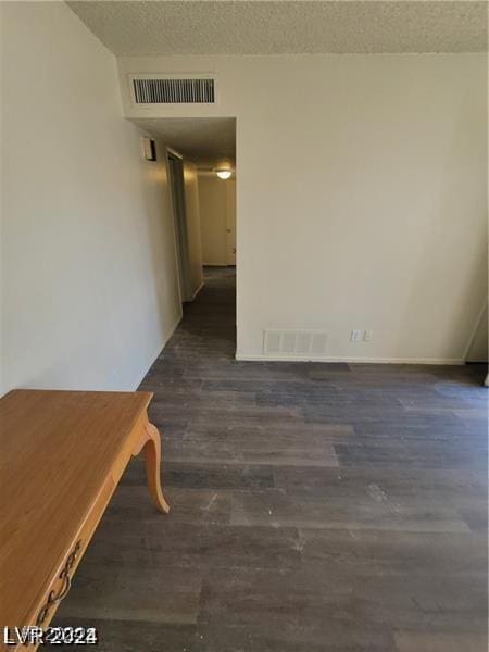 empty room with dark wood-type flooring and a textured ceiling