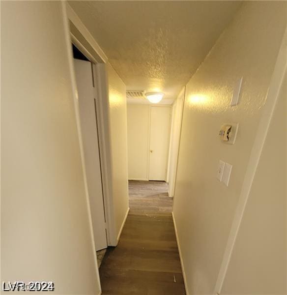 corridor featuring dark hardwood / wood-style flooring and a textured ceiling