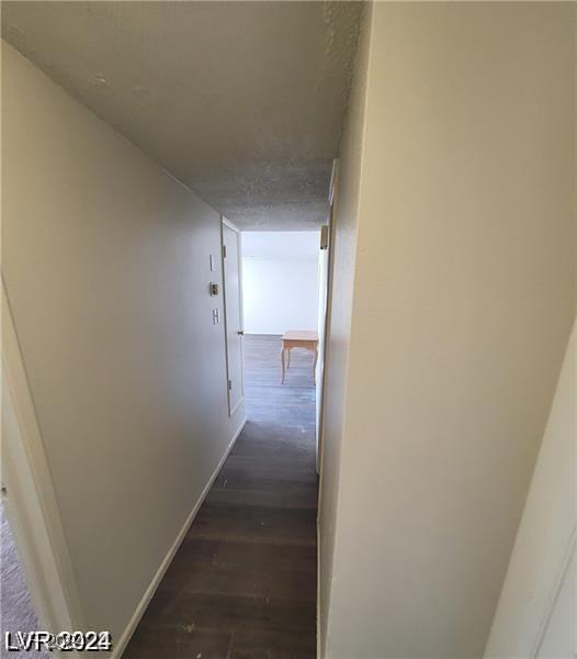 corridor with dark hardwood / wood-style floors and a textured ceiling