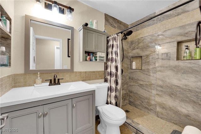 bathroom featuring walk in shower, toilet, tile walls, vanity, and decorative backsplash