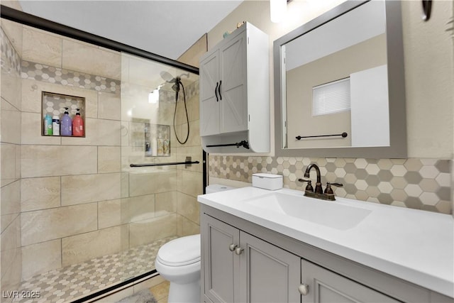 bathroom with vanity, backsplash, toilet, and a tile shower