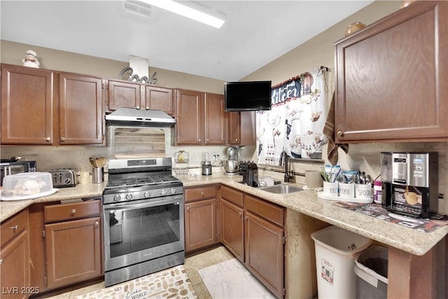 kitchen featuring sink, light stone counters, stainless steel gas range, and backsplash