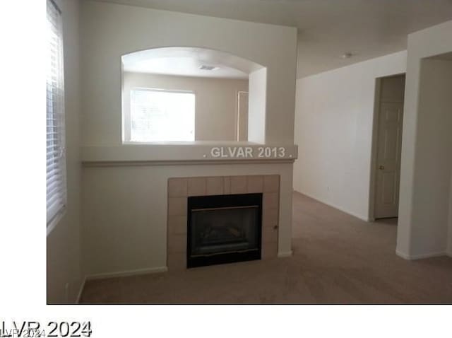 unfurnished living room featuring carpet floors and a tiled fireplace