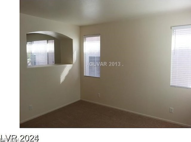 spare room with dark colored carpet