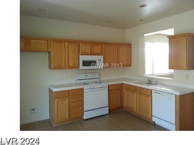 kitchen with dark tile patterned flooring, sink, and white appliances