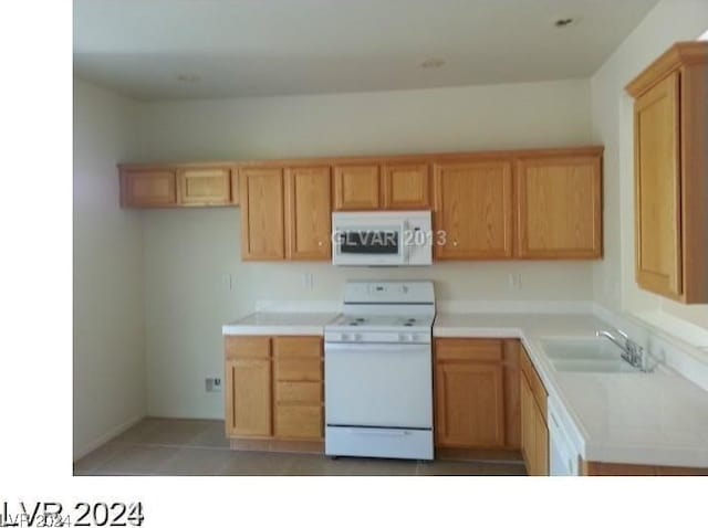 kitchen with white appliances, tile patterned floors, and sink