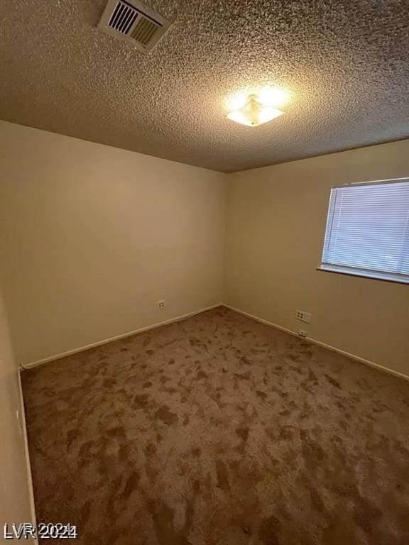 carpeted empty room featuring a textured ceiling