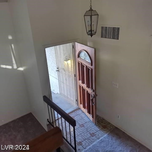 carpeted entryway with a chandelier