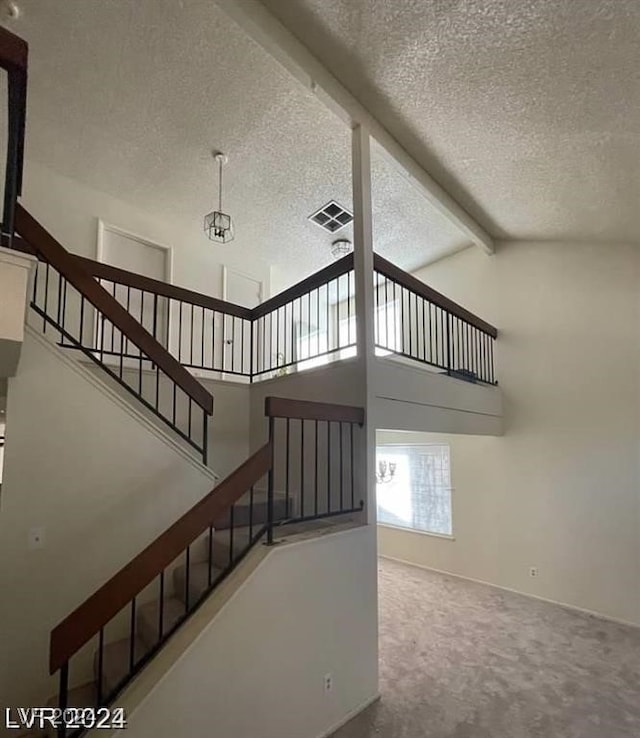 staircase featuring beamed ceiling, carpet, a textured ceiling, and high vaulted ceiling